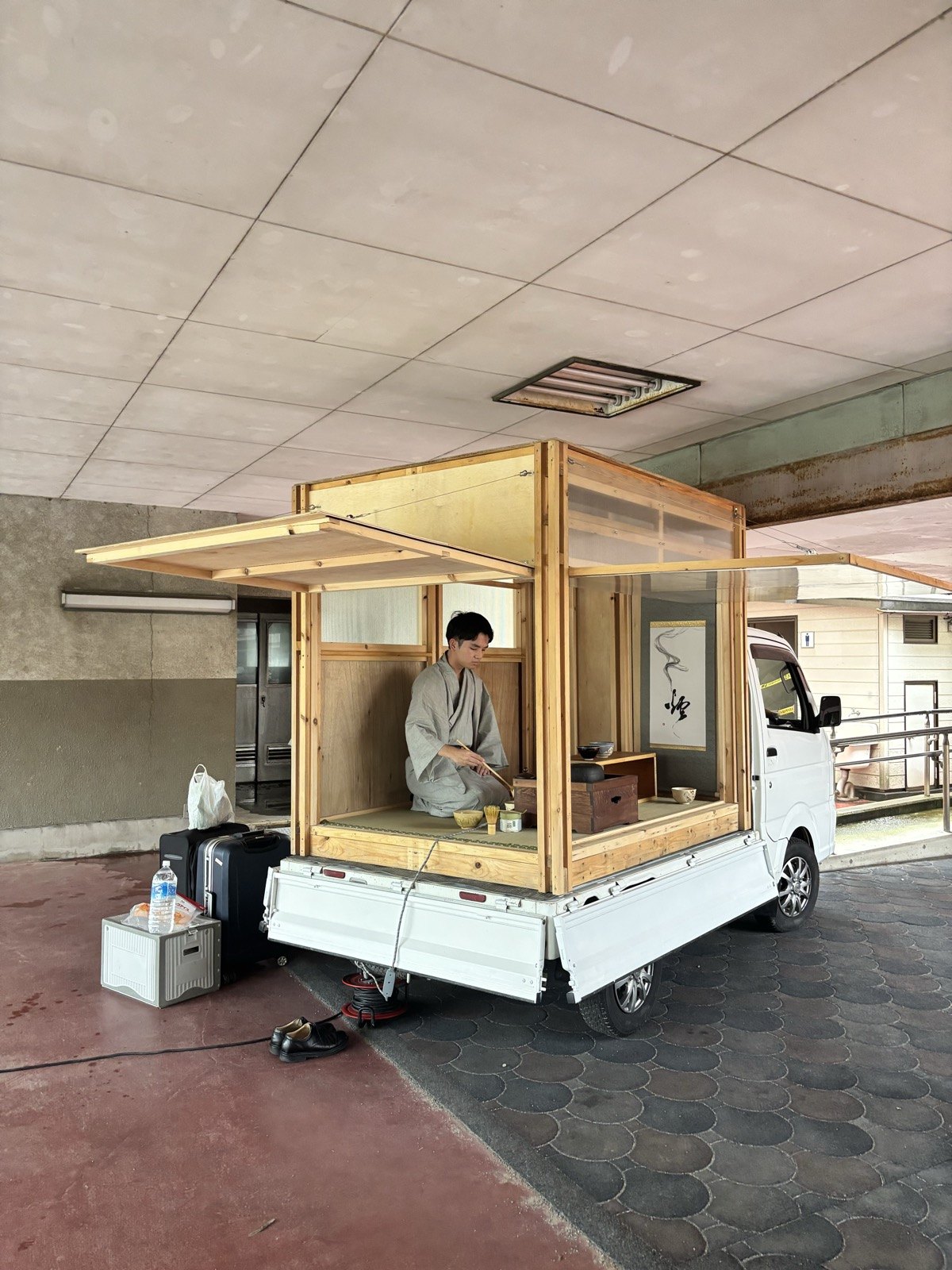 高七小のピロティに出店した軽トラ茶室と、茶を点てる亭主