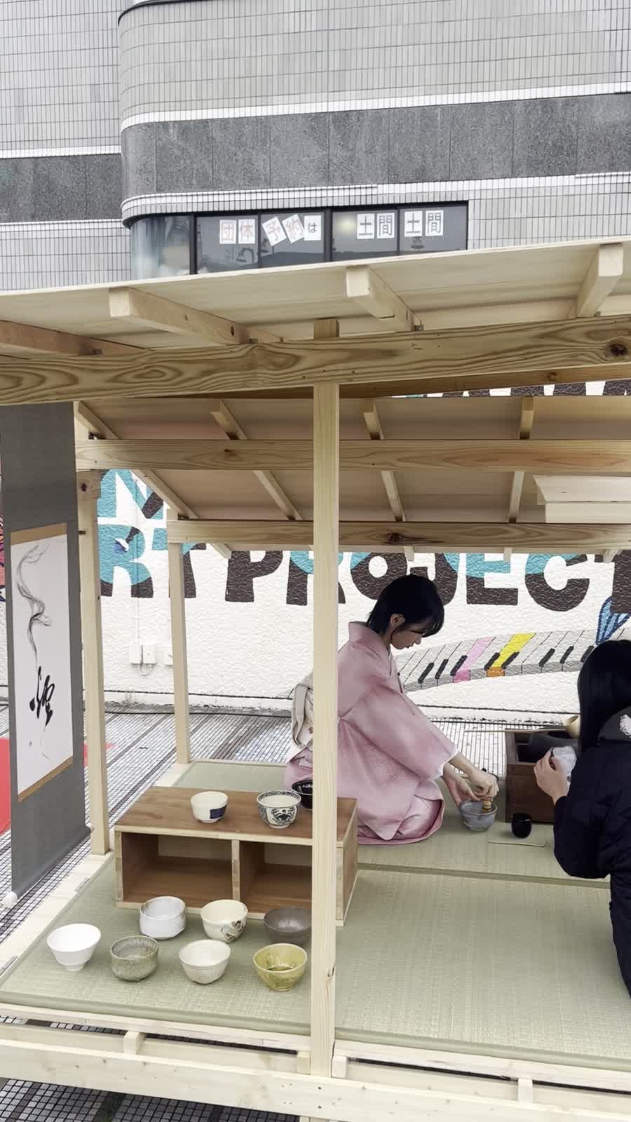 横浜の屋外会場に設けた流水庵の畳で、茶を点てる亭主